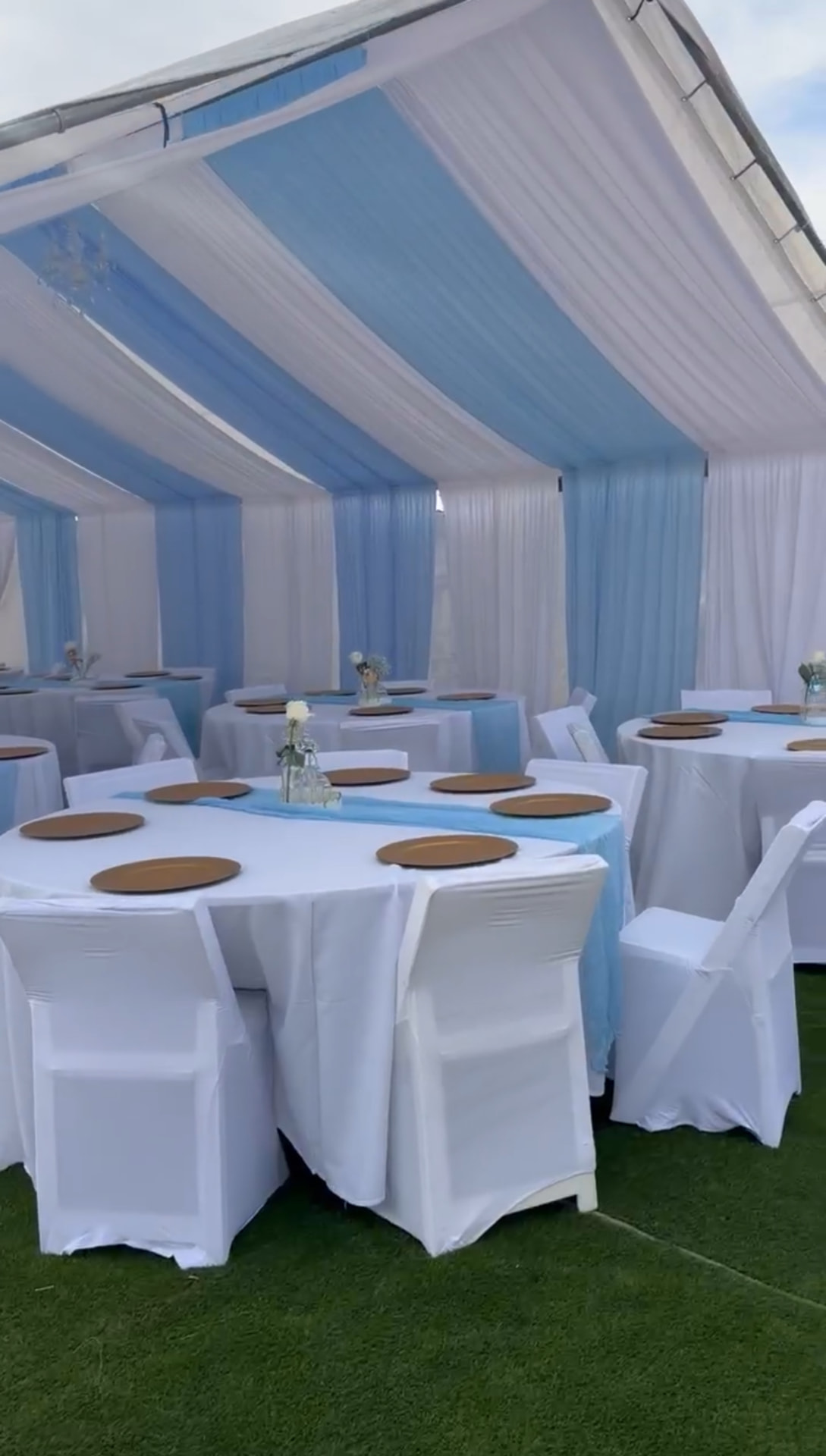 Outdoor Las Vegas event tent with white and blue ceiling draping, covered chairs and set banquet tables